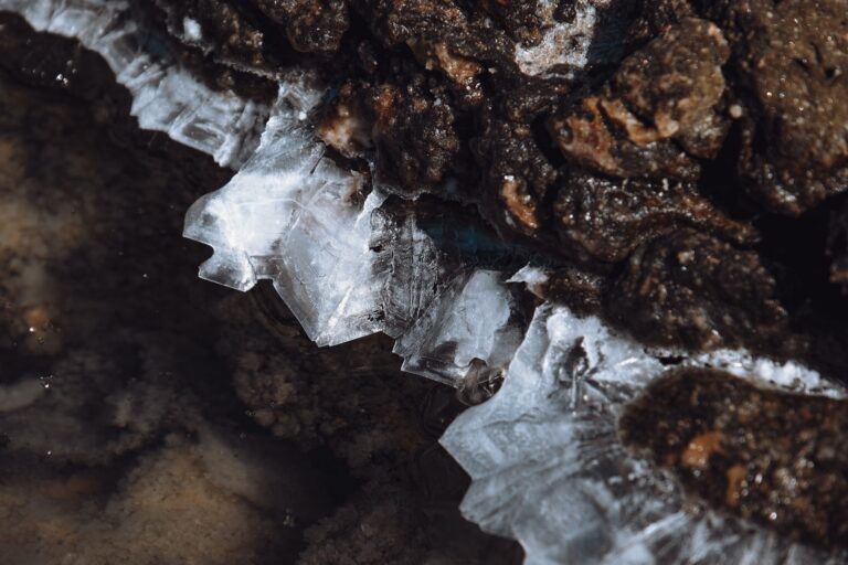 Detailed view of ice crystals forming on rough rocky surface during winter.