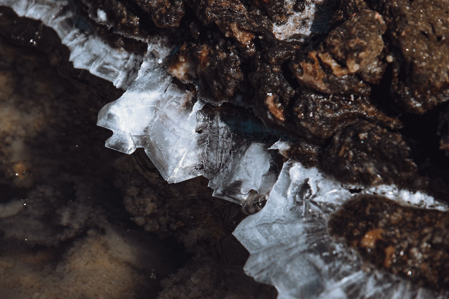 Detailed view of ice crystals forming on rough rocky surface during winter.