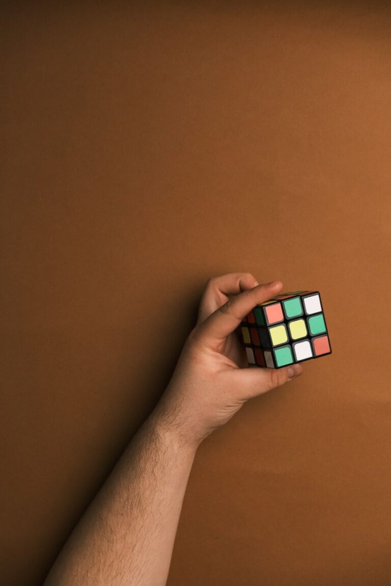 A hand holding a partially solved Rubik's Cube on a brown background; perfect for logic and strategy themes.