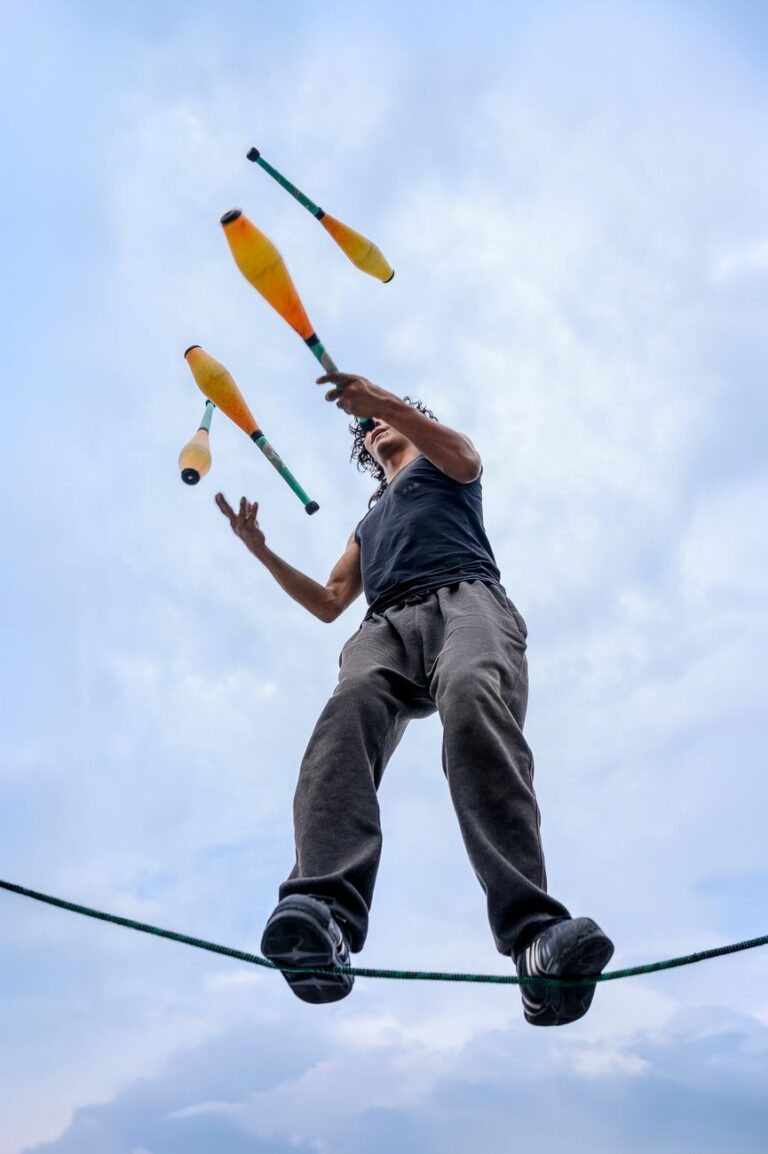 A skilled performer juggles on a tightrope, captured against a dramatic cloudy sky, showcasing balance and dexterity.